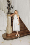 Woman in a white dress standing on a staircase in an elegant interior setting