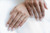 Close-up of two hands with rings on a white background