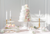 Decorative wedding cake with floral elements on a table with candles and pastries.