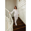 Woman in a white outfit standing on a staircase in an elegant interior setting