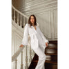 Woman in a white outfit standing on a staircase with decorative walls.