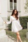 Woman in a white dress standing outdoors near a classical building