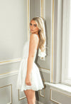 Woman in a white dress standing in a room with decorative walls.