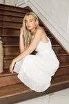 Woman in a white dress sitting on wooden stairs
