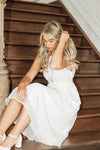 Woman in a white dress sitting on wooden stairs